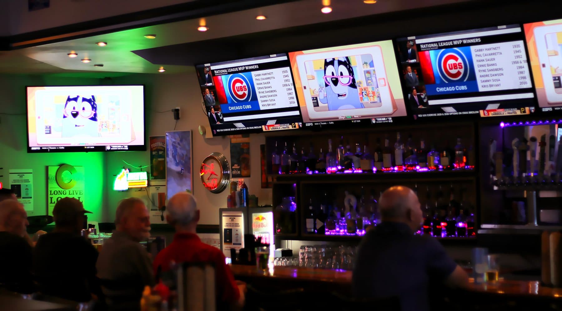 Regulars at The 303 Sports Grill, a sports bar in Lone Tree, under a wall of TVs and green neon